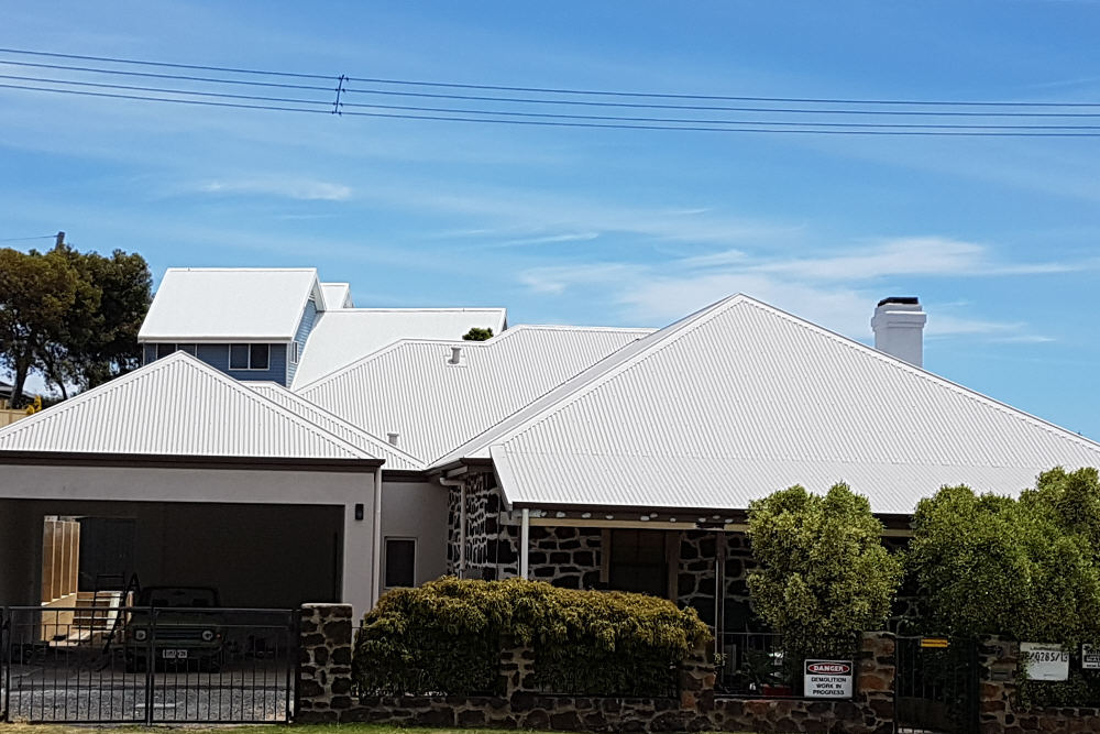 Split image of old house elevation, showing old tile roof before and new Colorbond roof after